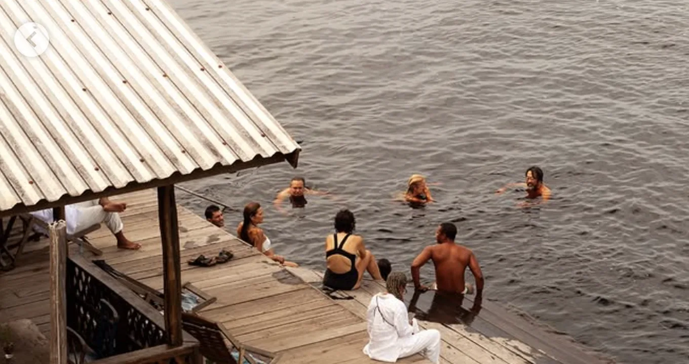 Banhistas num flutuante de madeira sobre as águas escuras do Rio Negro