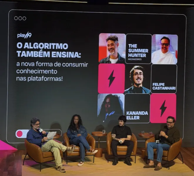 Painel do The Summer Hunter num palco, com convidados sentados diante de um telão