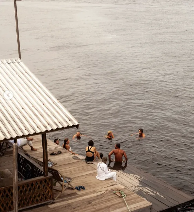 Banhistas num flutuante de madeira sobre as águas escuras do Rio Negro