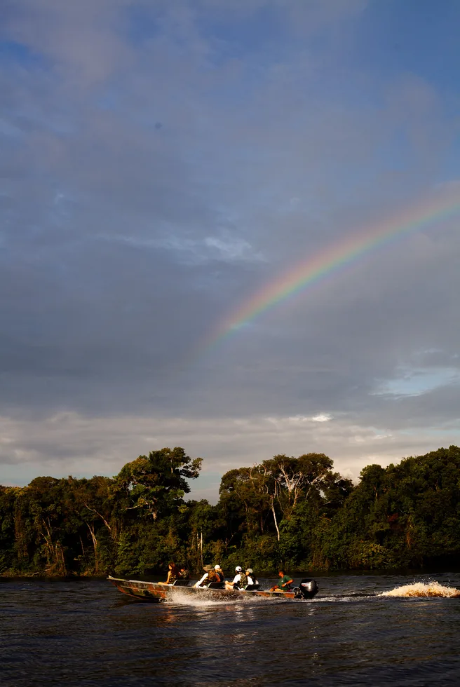 Arco-íris sobre o rio ao entardecer, com um barco ao longe