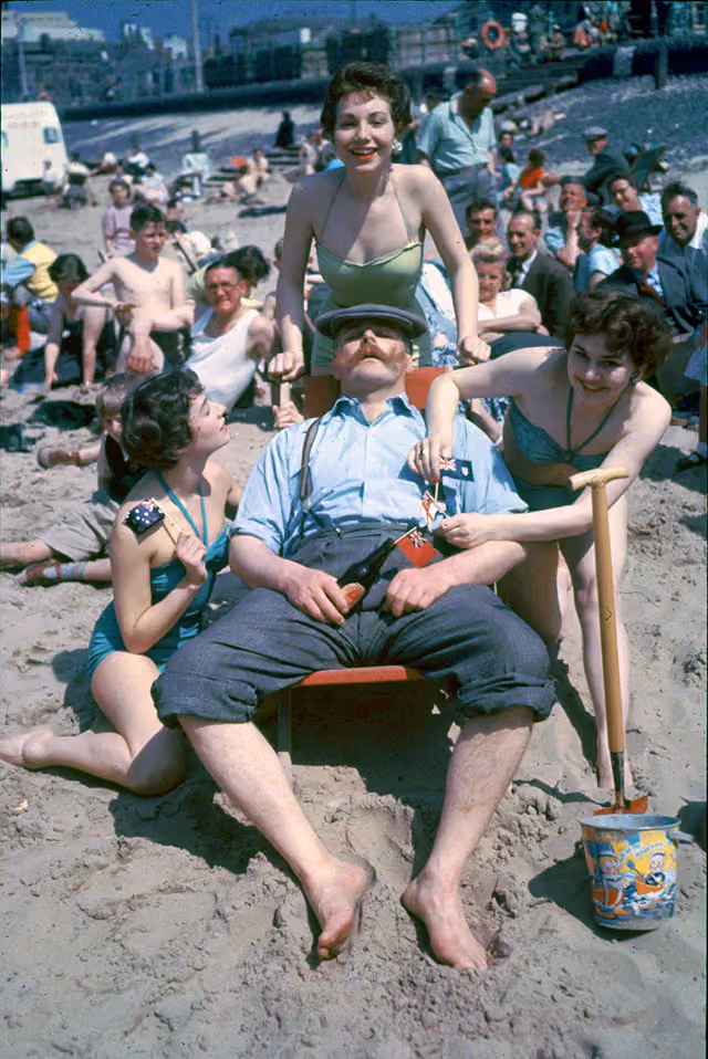 Comedian Jimmy Edwards (1920 - 1988) surrounded by Tiller girls as he relaxes in a deckchair on the beach at Blackpool. They are all appearing in a show on the pier for the summer season. (Photo by John Chillingworth/Getty Images)