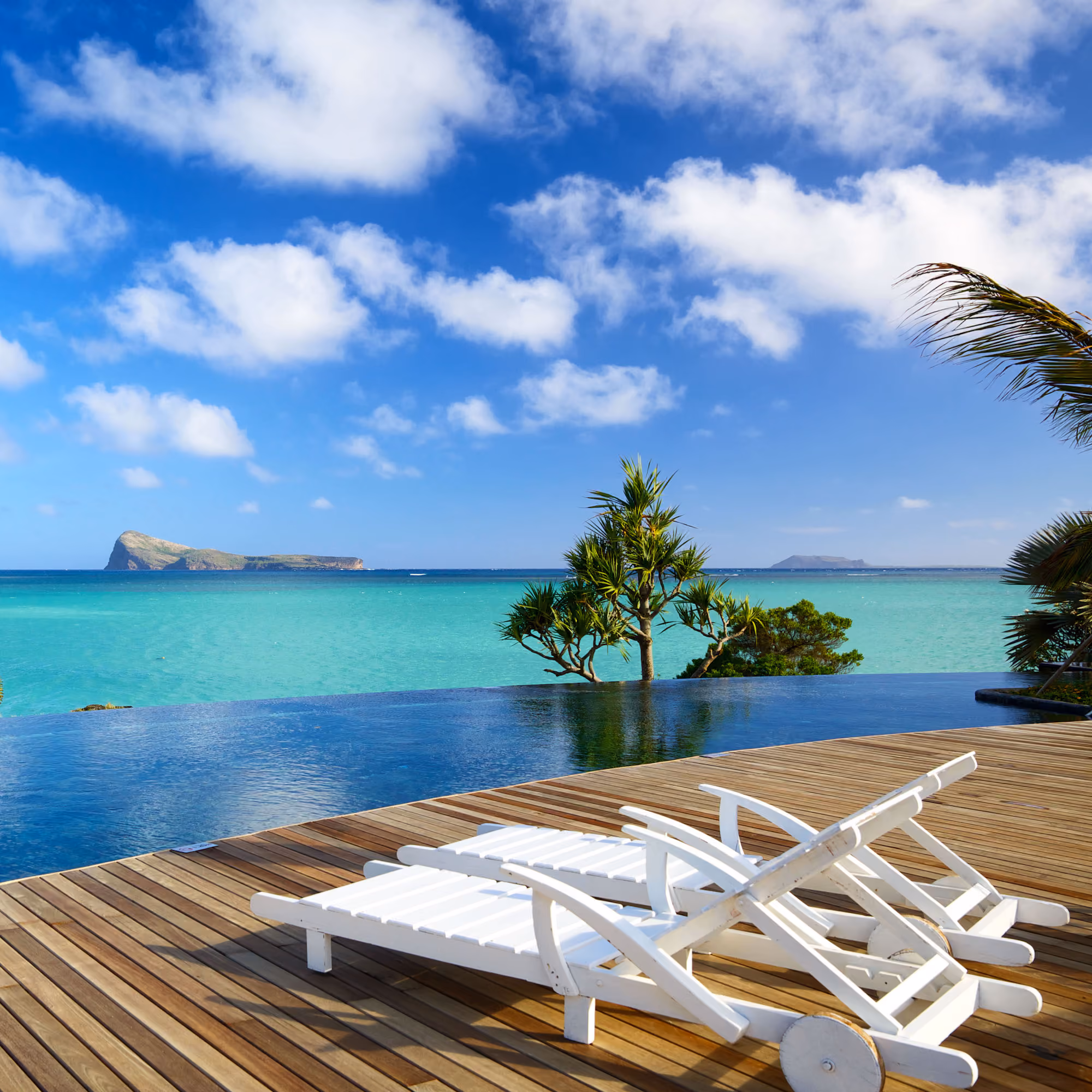 Swimming pool with deckchairs and Indian Ocean in Mauritius